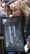 A New York resident holds a World Trade Center poster in street prayers in Manhattan near the destruction.